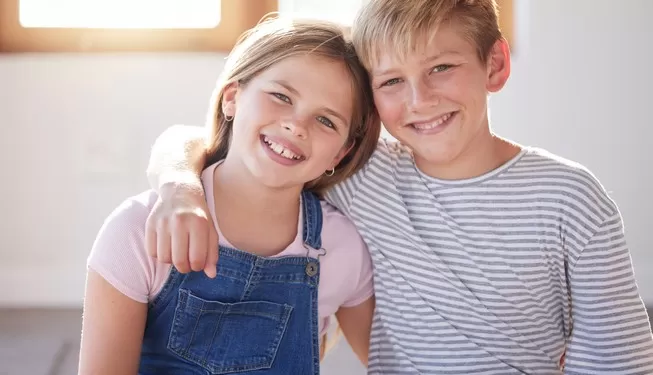 Produktkategoriebild mit zwei Kindern: Junge und Mädchen nehmen sich in den Arm und lächeln in die Kamera