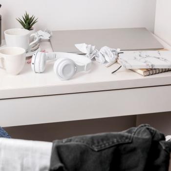 Unordentlicher Schreibtisch mit Kopfhörern, Tassen und Papier – Symbolbild für Reizüberflutung und Alltagschaos bei ADHS